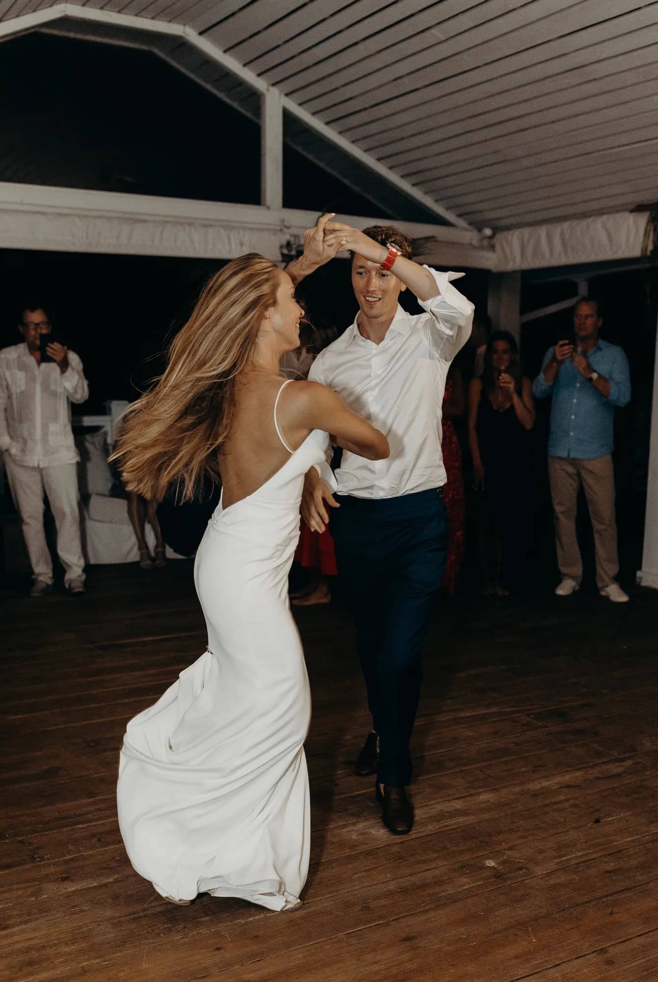 Couple spinning on the dance floor during their first dance while guests watch