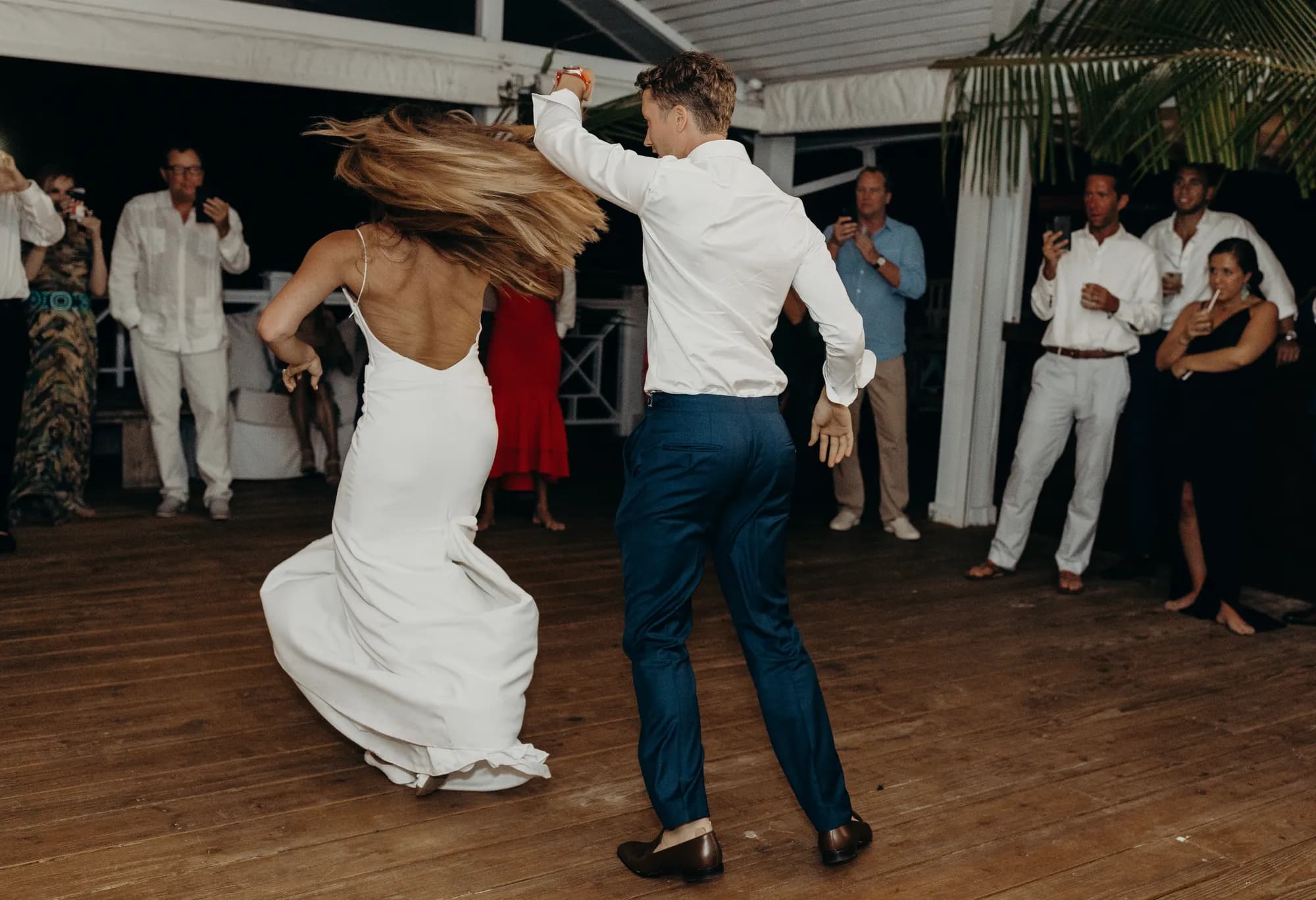 Couple spinning on the dance floor during their first dance while guests watch