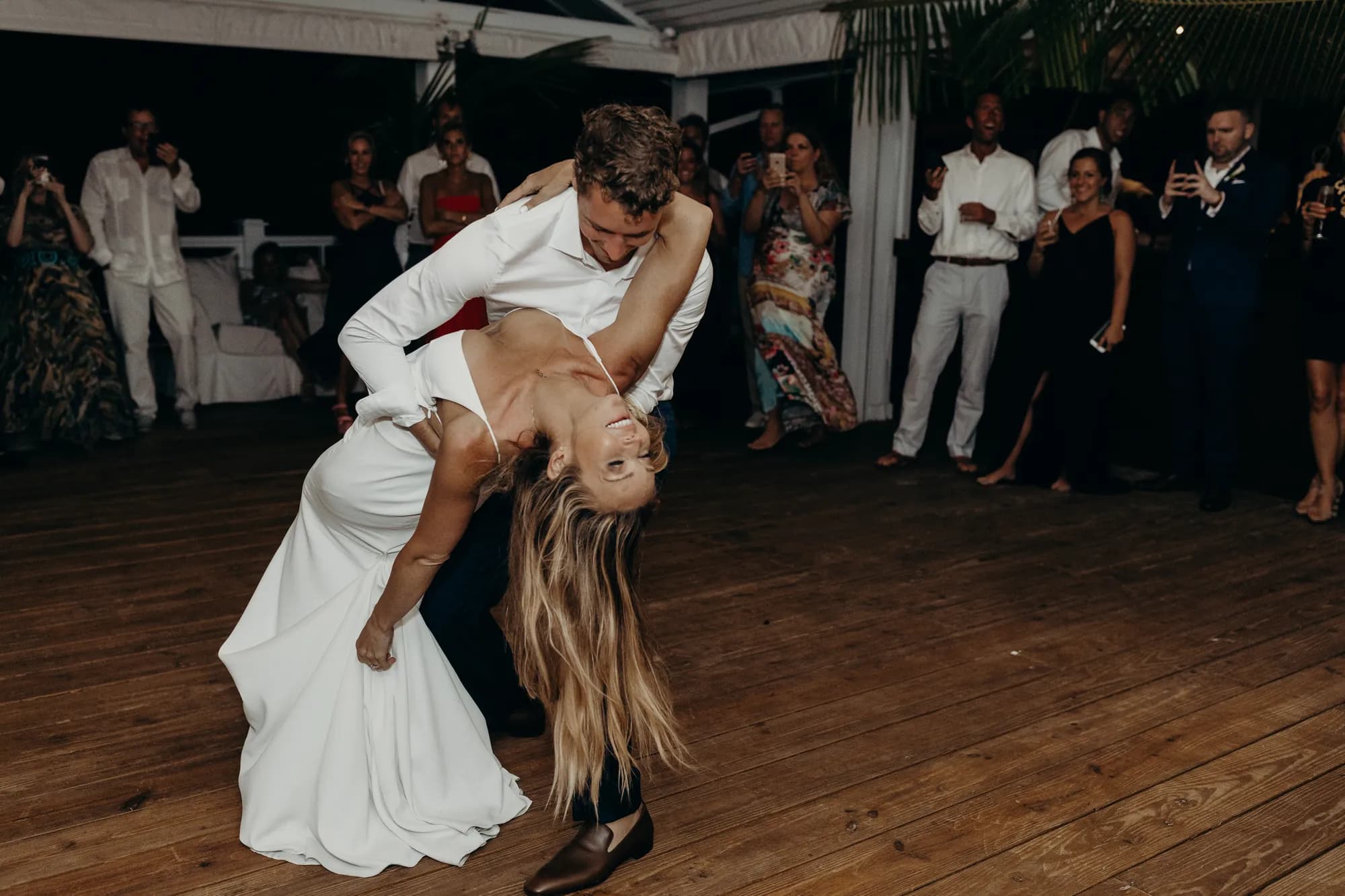 Bride and groom in a dip during their first dance while guests watch